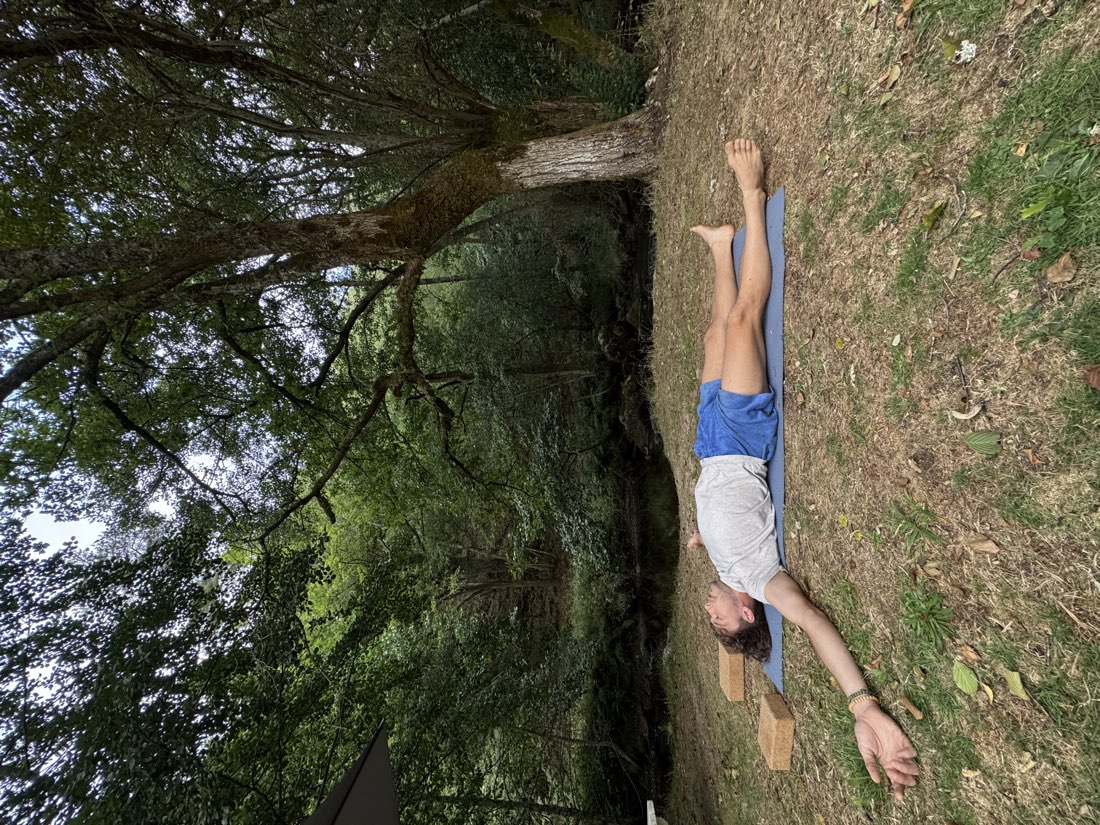 Antoine allongé sur le dos sur un tapis, dans l'herbe, en respiration